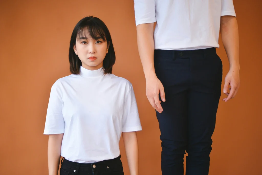 Short woman and tall person standing together demonstrating height difference and short people problems in everyday situations
